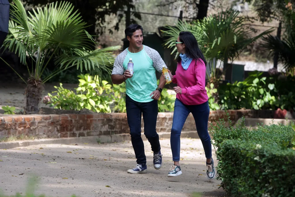 Pareja con botella en la mano de agua Rawganic sabor Aloe Vera con arándano y Piña