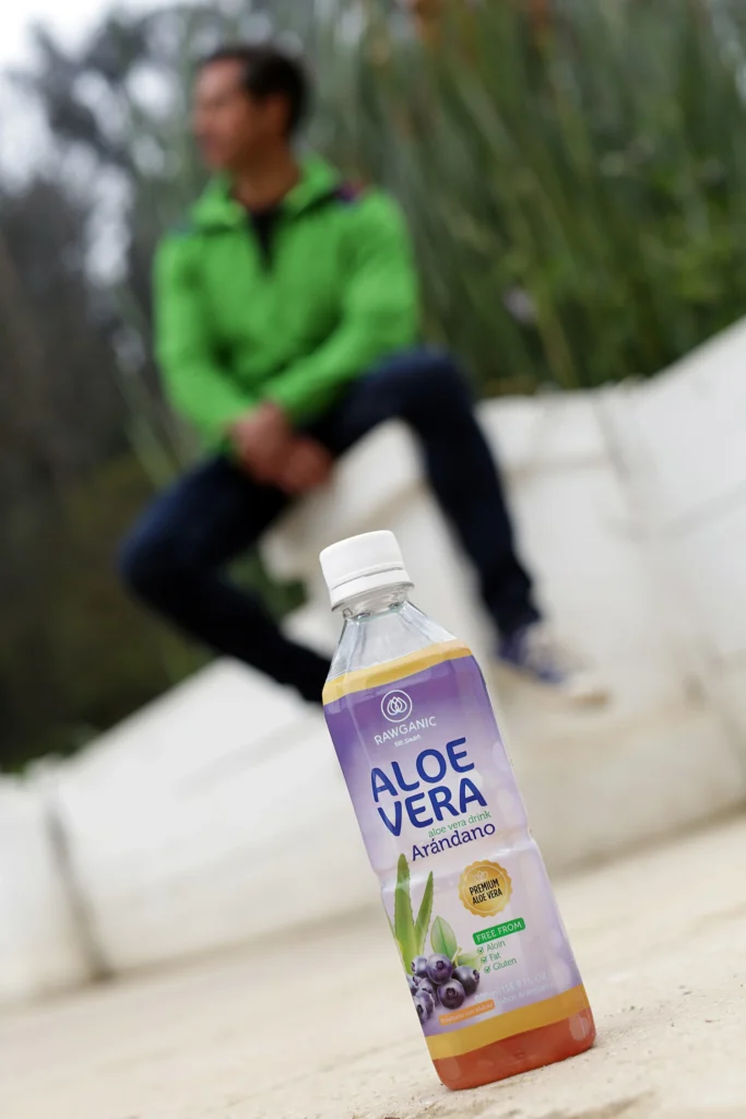 Botella de agua Rawganic sabor Aloe Vera con arándano sobre fondo natural