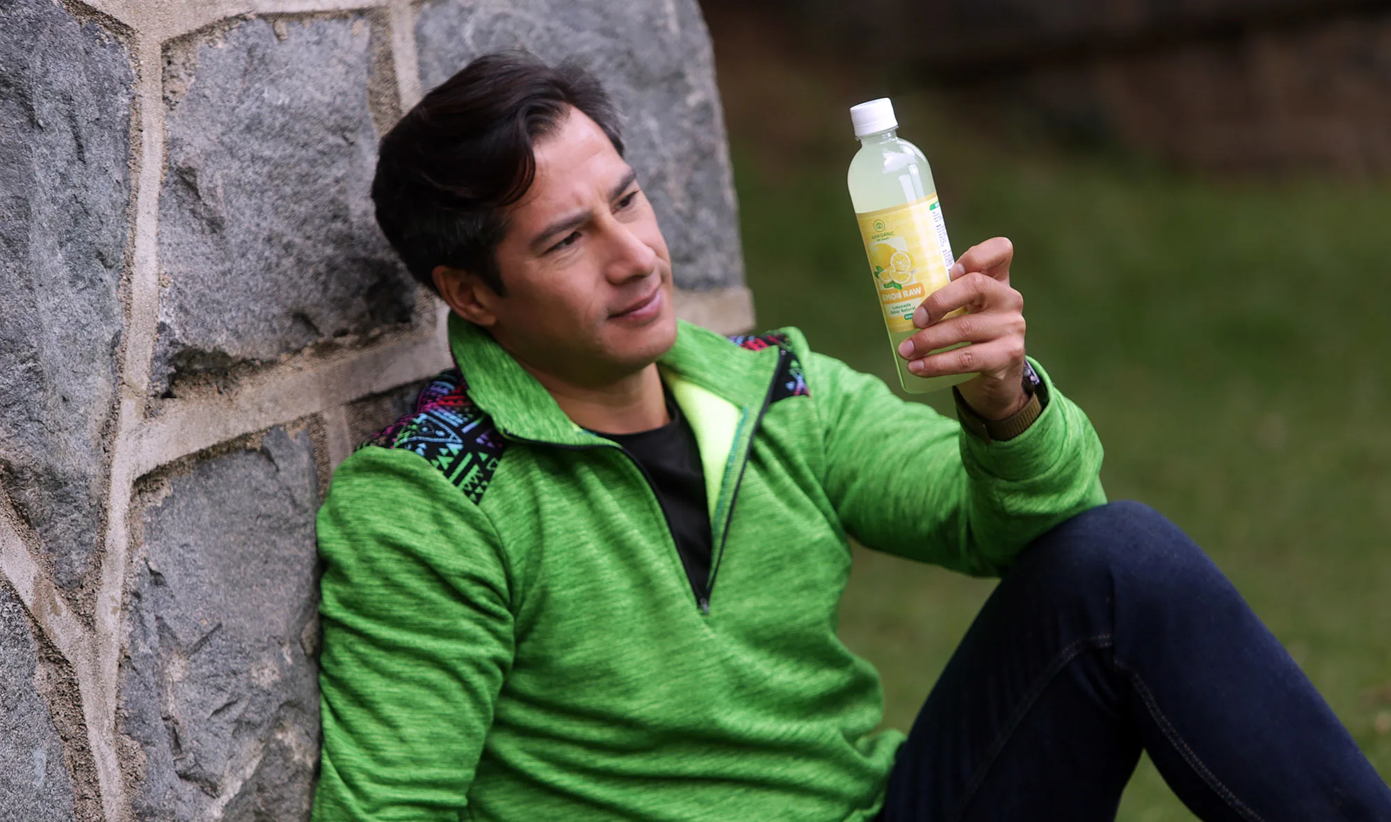 Botella de limonada Lemon Raw en la mano de modelo con fondo natural